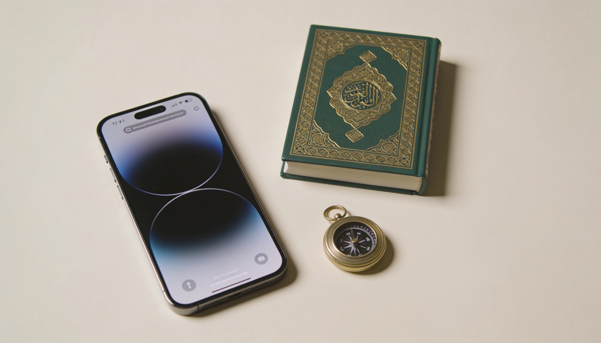 Krem zemin üzerinde bir telefon, yeşil-altın bir Kur'an ve pirinç bir pusula